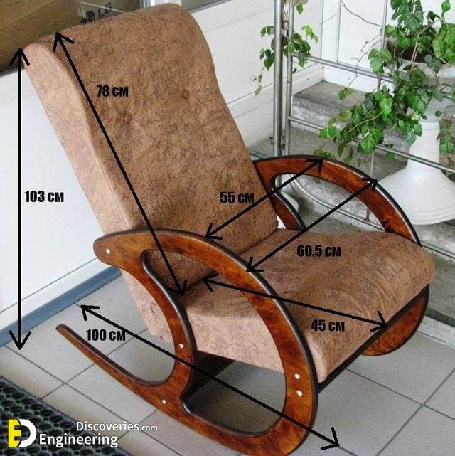 a wooden rocking chair sitting on top of a tiled floor next to a potted plant