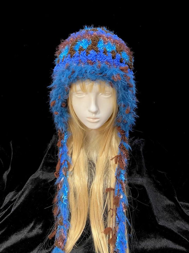 a mannequin head wearing a blue and brown knitted hat with feathers on it