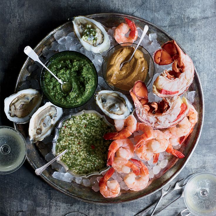 a platter with shrimp, oysters, and guacamole on it