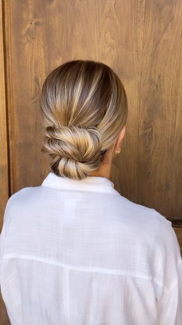 a woman with blonde hair is standing in front of a wooden door wearing a white shirt