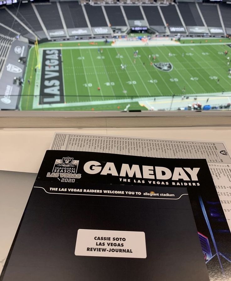 a book sitting on top of a table in front of a football stadium filled with fans