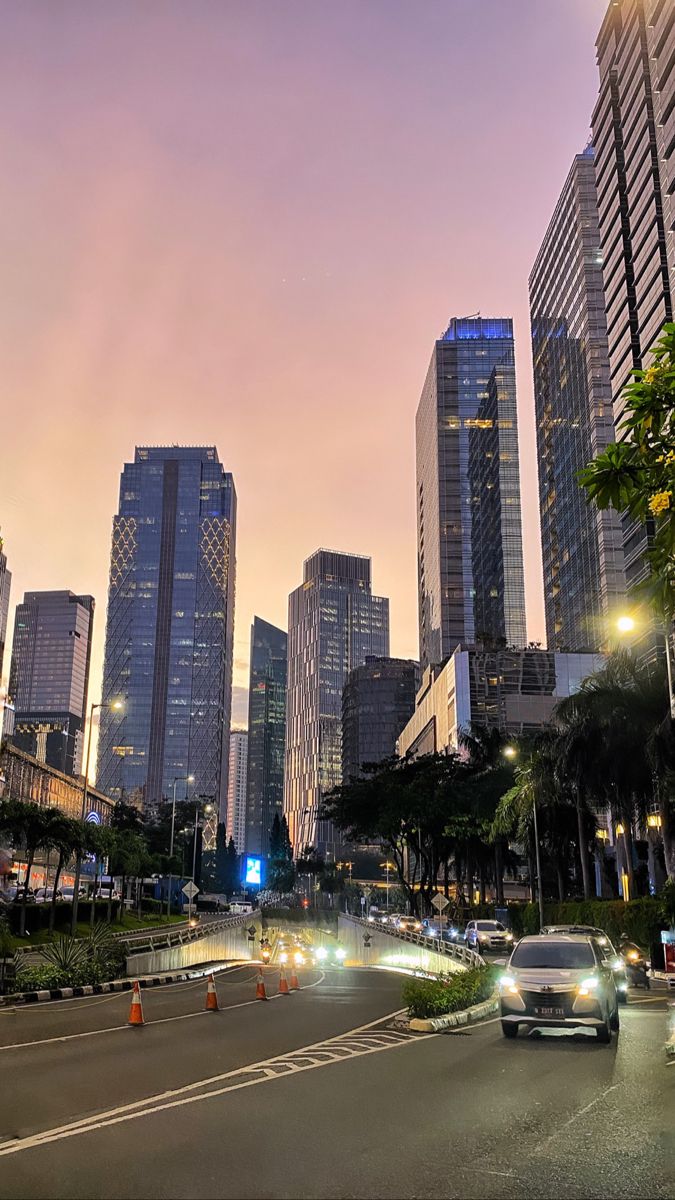 a city street filled with lots of traffic next to tall buildings in the evening time