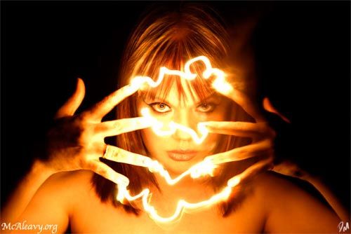 a woman holding her hands in front of her face with the light painted on her face