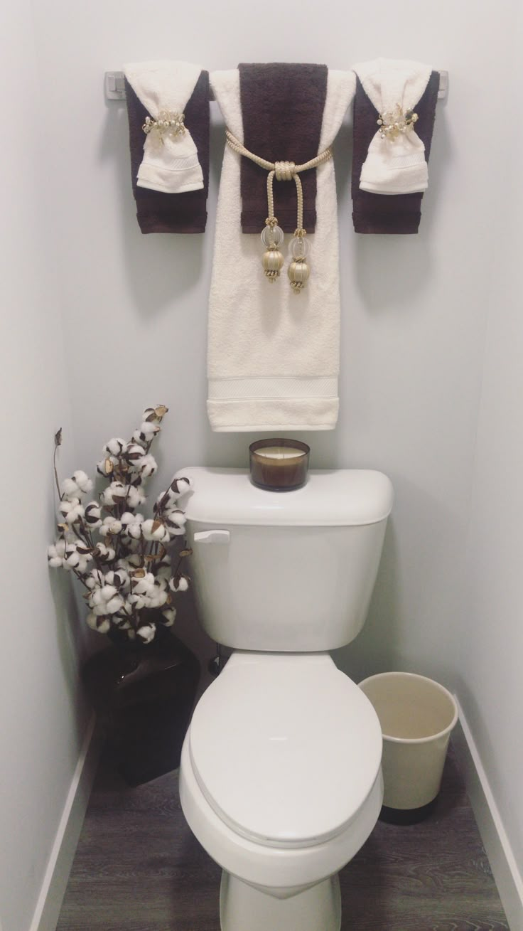 a white toilet sitting in a bathroom next to a towel rack and flower pot on top of it