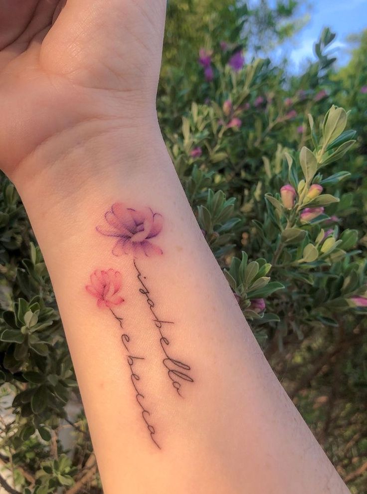 a woman's wrist with flowers on it and the word love written in cursive writing