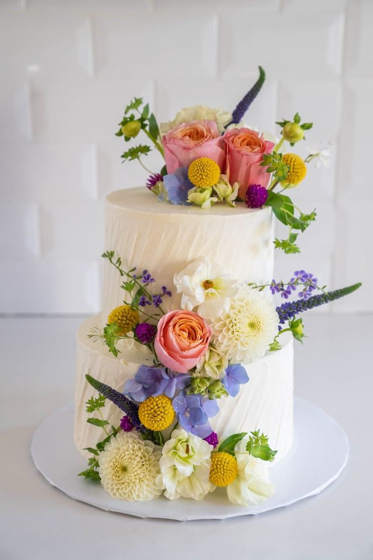 a three tiered white cake with flowers on top