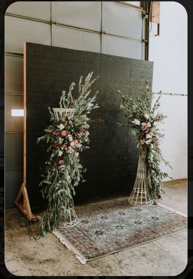 two tall floral arrangements on display in front of a black backdrop with white and pink flowers