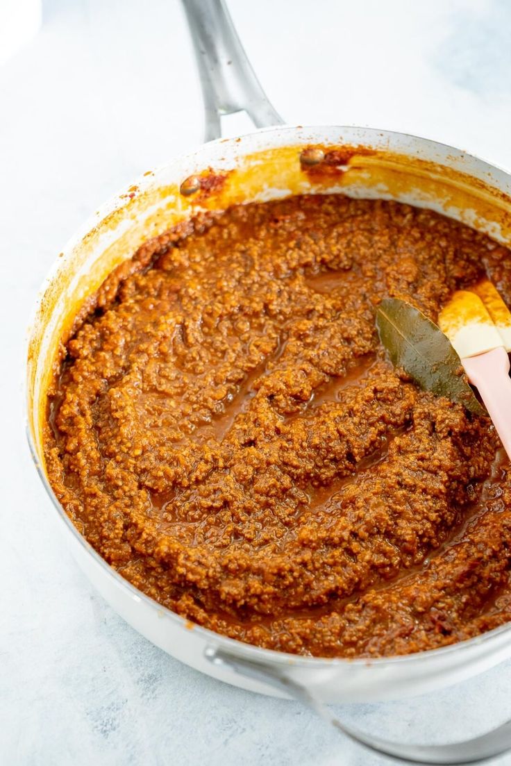 a pot filled with some kind of food on top of a white countertop next to a spatula