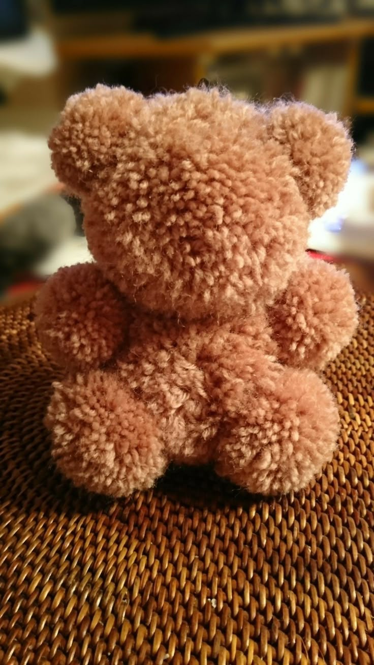 a brown teddy bear sitting on top of a woven table cloth covered in flecks