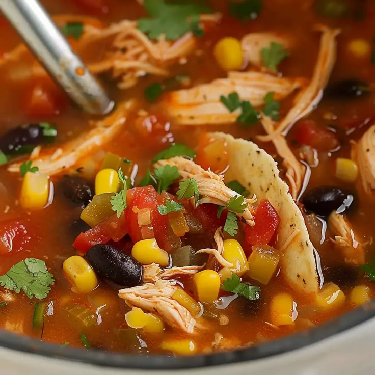 a bowl of chicken tortilla soup with corn and black beans