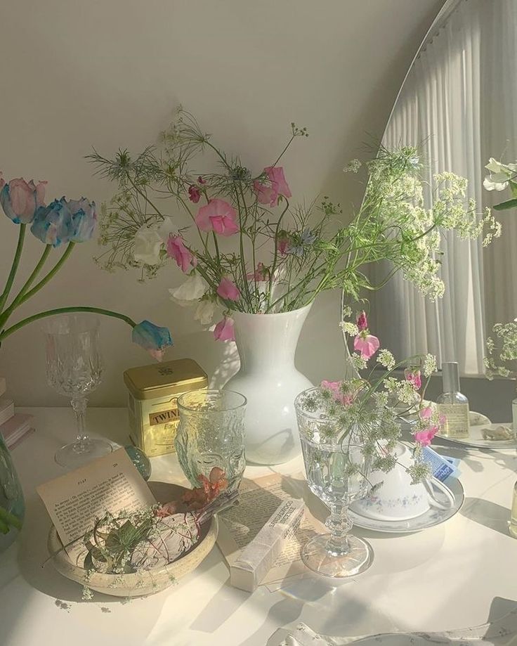 a table topped with vases filled with flowers next to books and other items on top of it