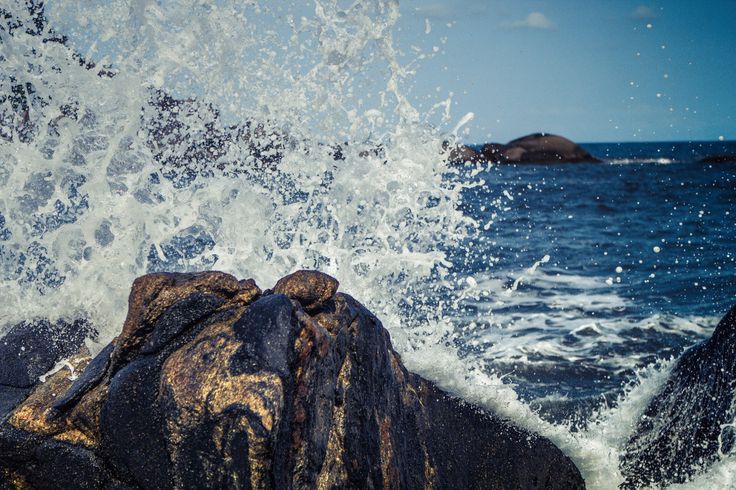 the water splashes on rocks in front of an island