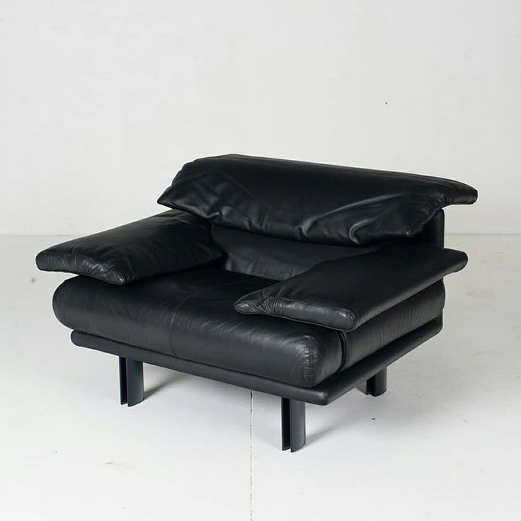 a black leather chair sitting on top of a white floor