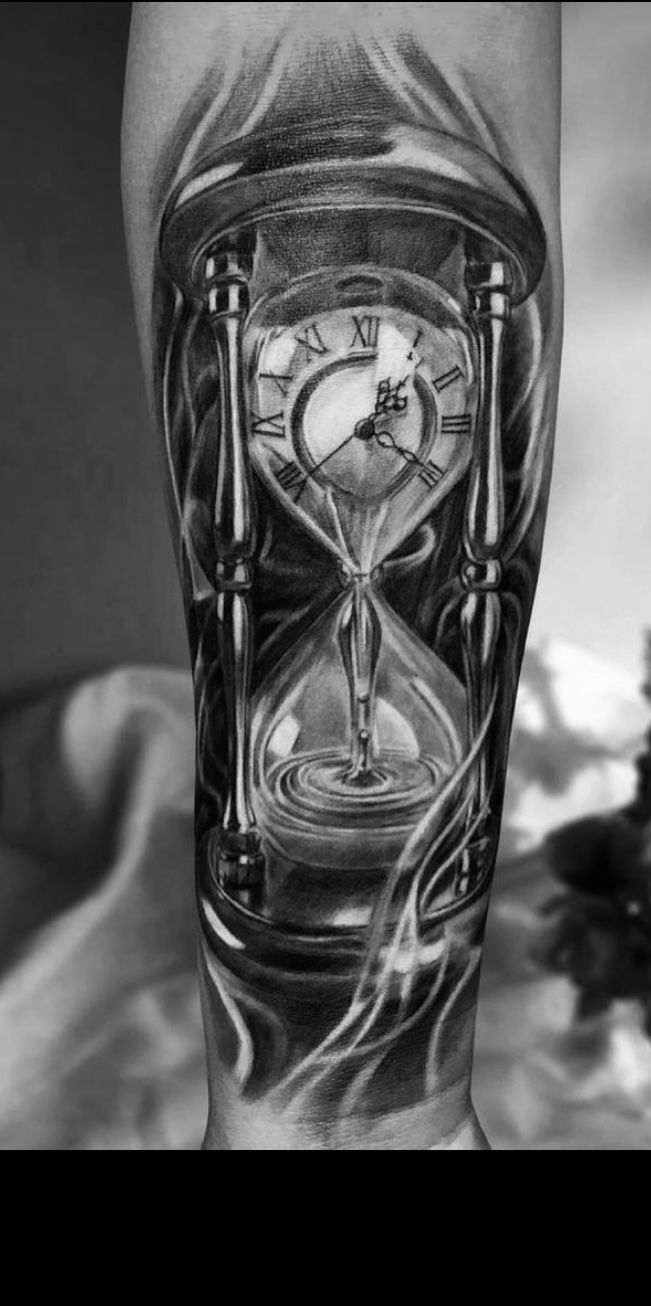 a man's leg with an hourglass tattoo on it and the clock is in flames