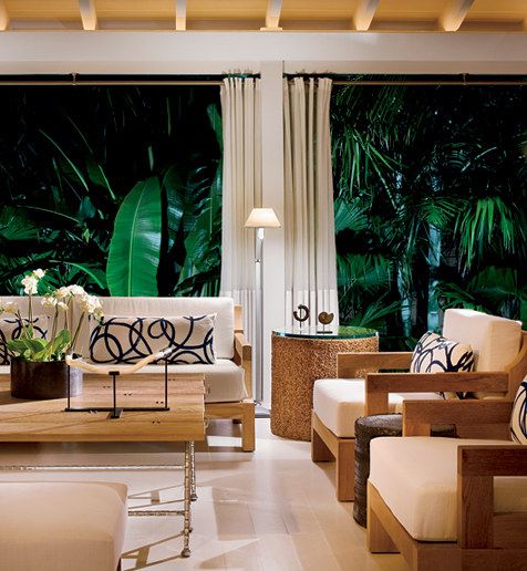 a living room filled with lots of furniture next to a window covered in greenery