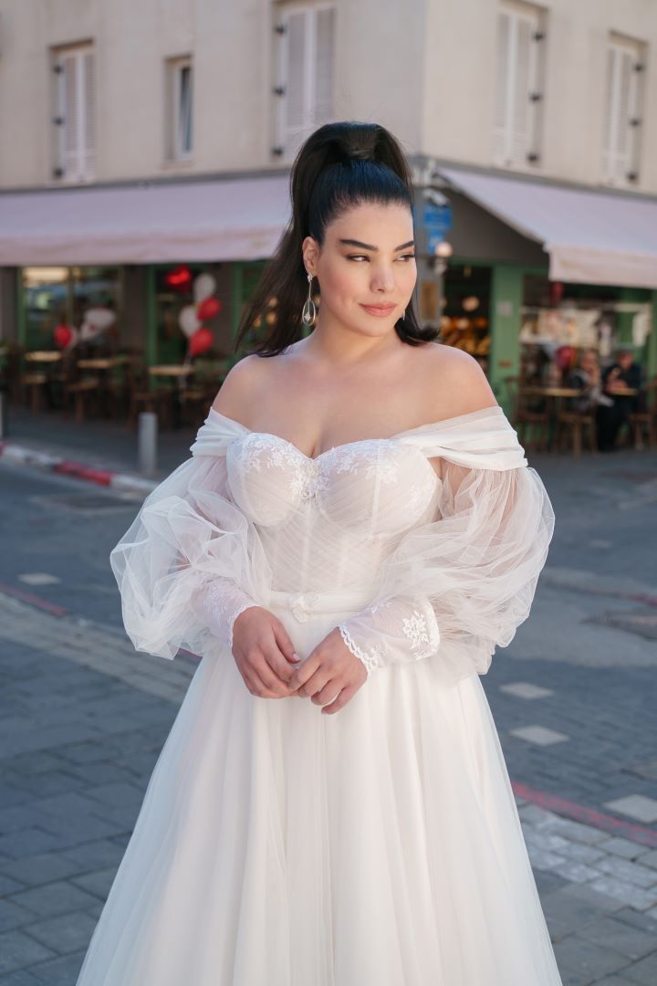 a woman in a white dress is standing on the street with her hands behind her back