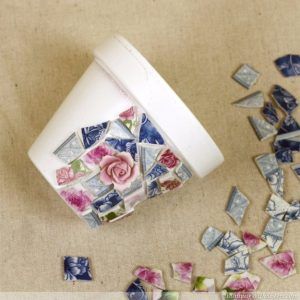 a white cup sitting on top of a table filled with broken tiles and pink flowers