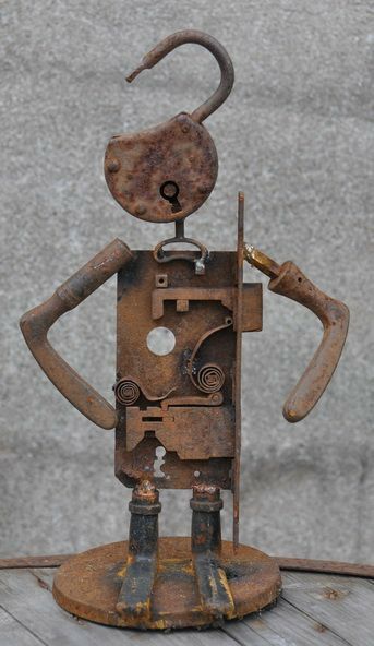 an old rusty metal robot standing on top of a wooden table