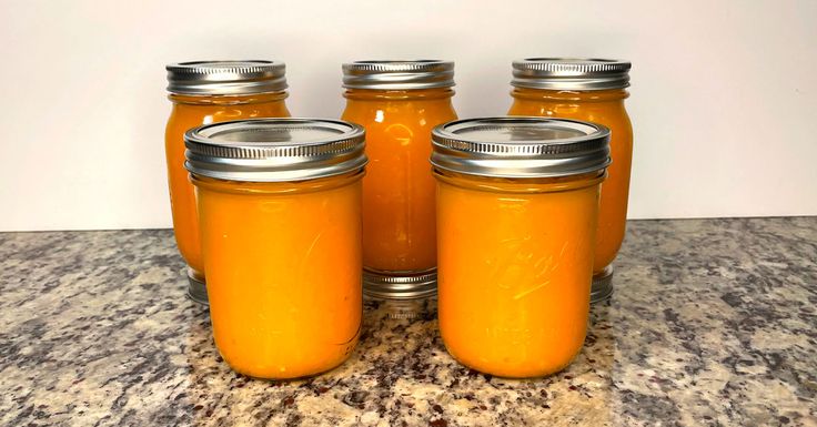 four jars filled with orange liquid sitting on top of a counter