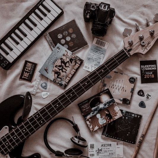 an electric bass guitar, headphones, and other items laid out on a bed