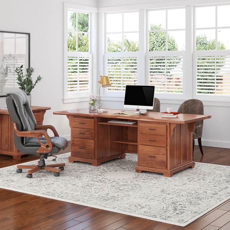 an office desk with two chairs and a computer monitor on it in front of windows