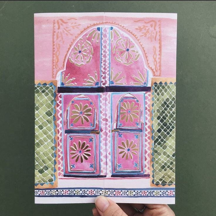 a hand holding up a card with an image of a pink and green door on it