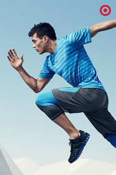 a man in blue shirt and black shorts jumping up into the air with a red frisbee