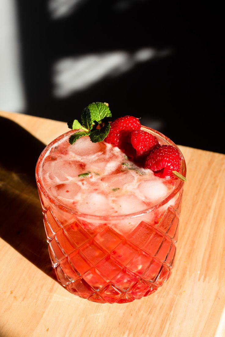 a glass filled with ice and strawberries on top of a wooden table