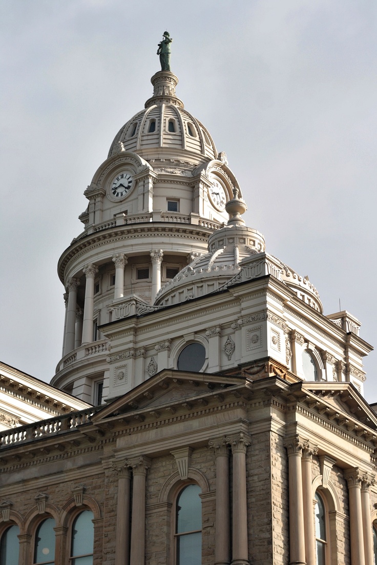 a large building with a clock on the top of it's tower and sky in the background