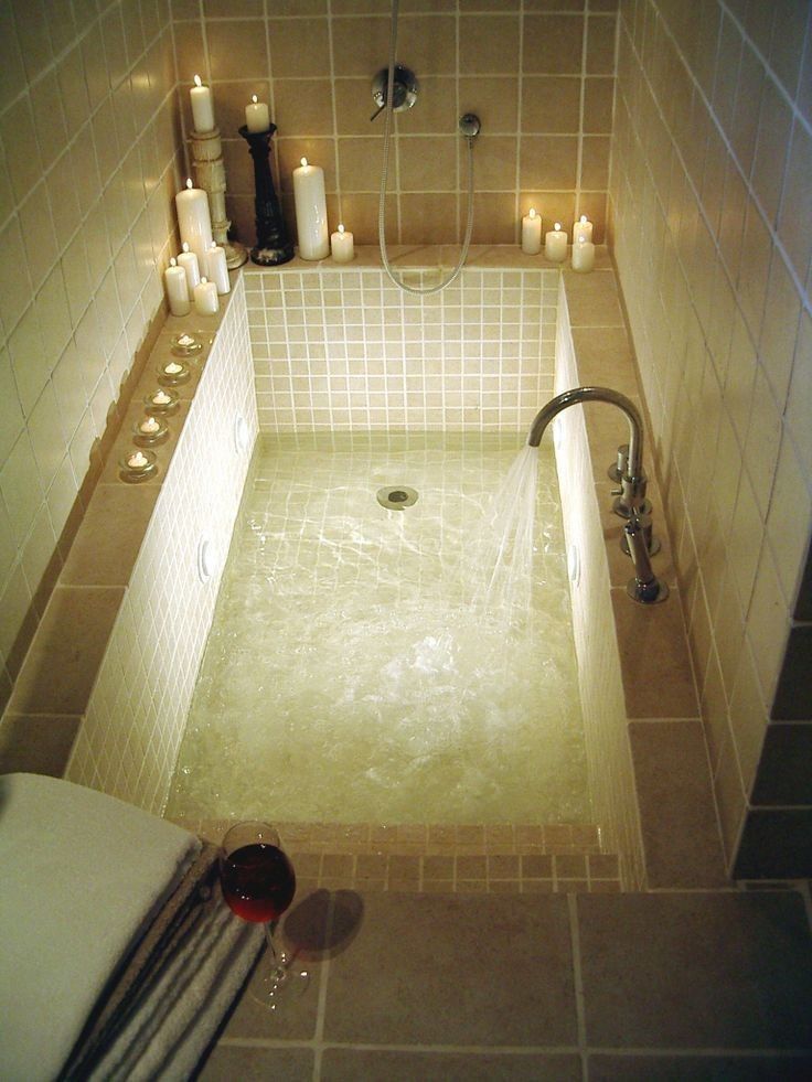 a bathtub filled with water surrounded by candles