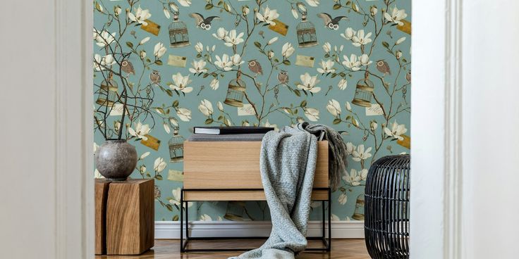 a blue wallpaper with white flowers and birds on it in a hallway next to a dresser