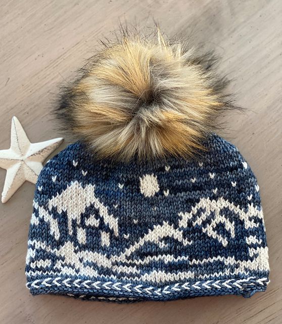 a knitted hat with a star on the side and a pom - pom