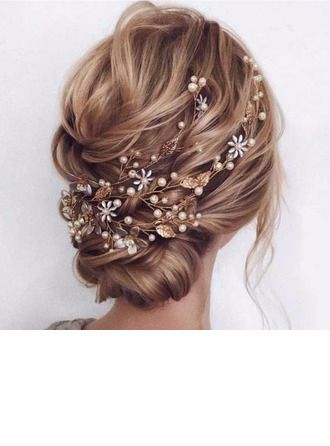 a woman wearing a hair comb with flowers and pearls on it's head, in front of a white wall