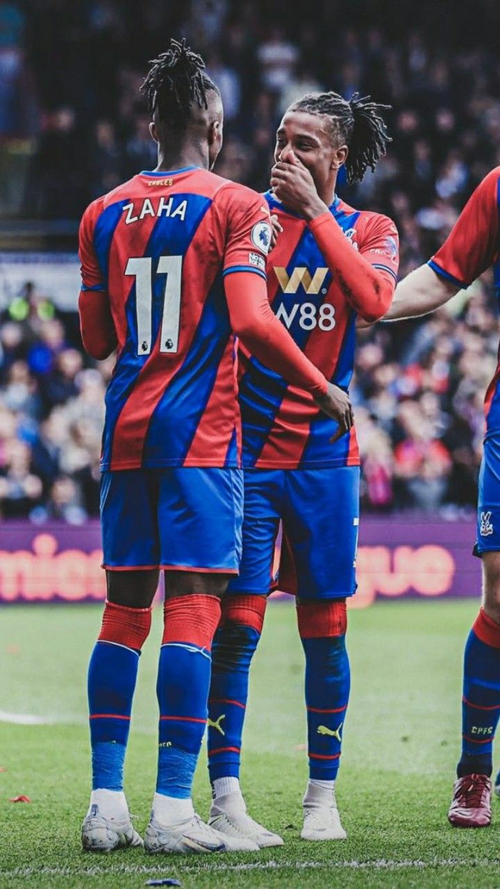 three soccer players are standing on the field and one is covering his face with his hands