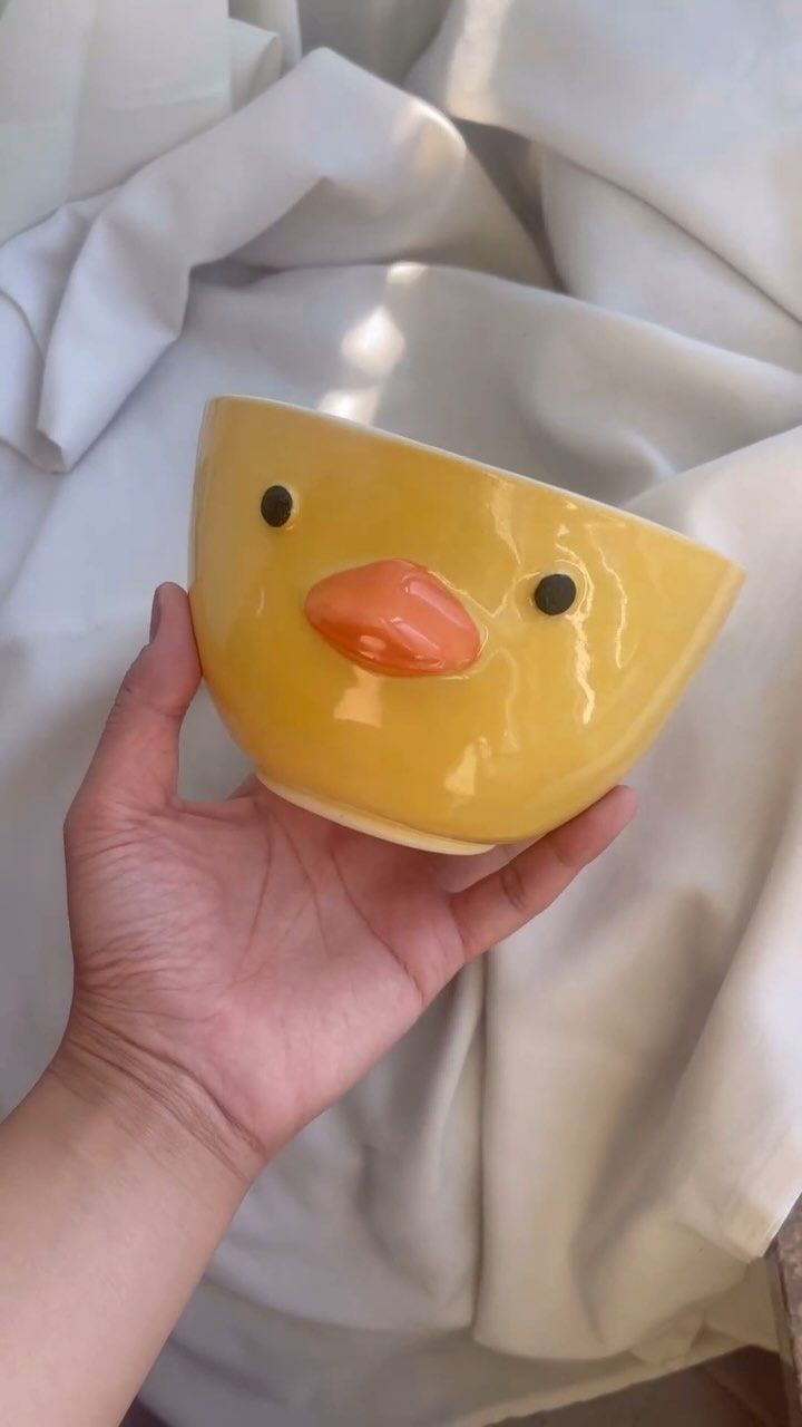 a hand holding a yellow ducky shaped bowl