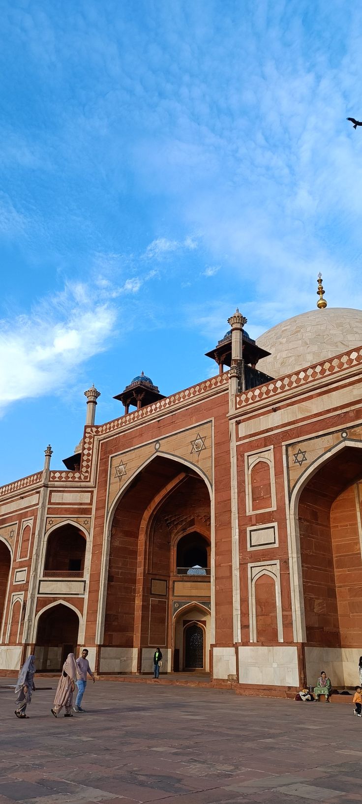 two people walking in front of a large building with arches and minarets on top