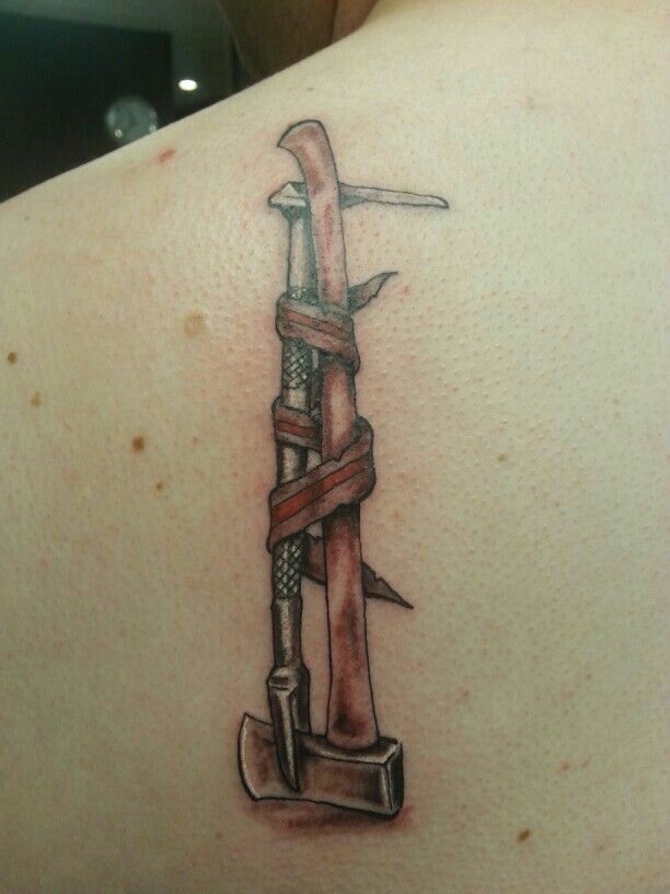 a tattoo on the back of a woman's shoulder with an old style hammer and rope wrapped around it