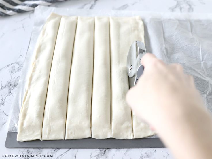 a person is cutting dough into strips on a board