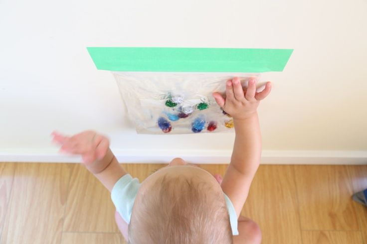 a young child reaching up to put something in a bag on top of the floor