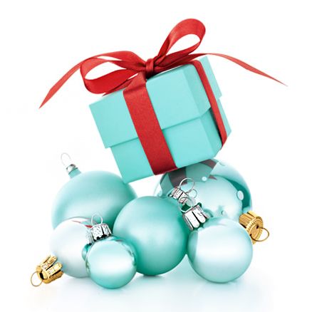 a blue gift box with red ribbon on top of some christmas baubles and ornaments