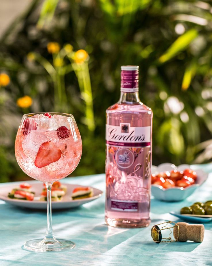 a bottle of pink wine sitting on top of a table next to plates of food