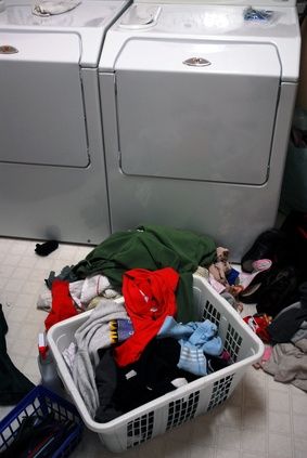 a laundry basket filled with clothes next to two washers