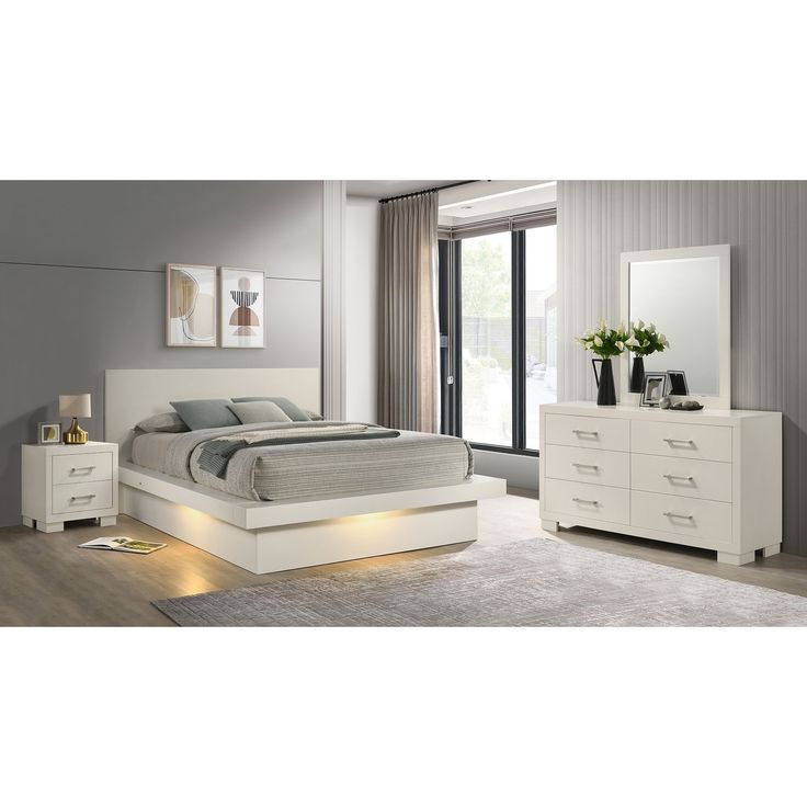 a white bed sitting in a bedroom next to a dresser with drawers and a mirror