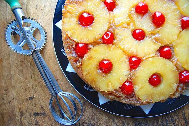 a pineapple upside down cake on a plate with fork and knife next to it