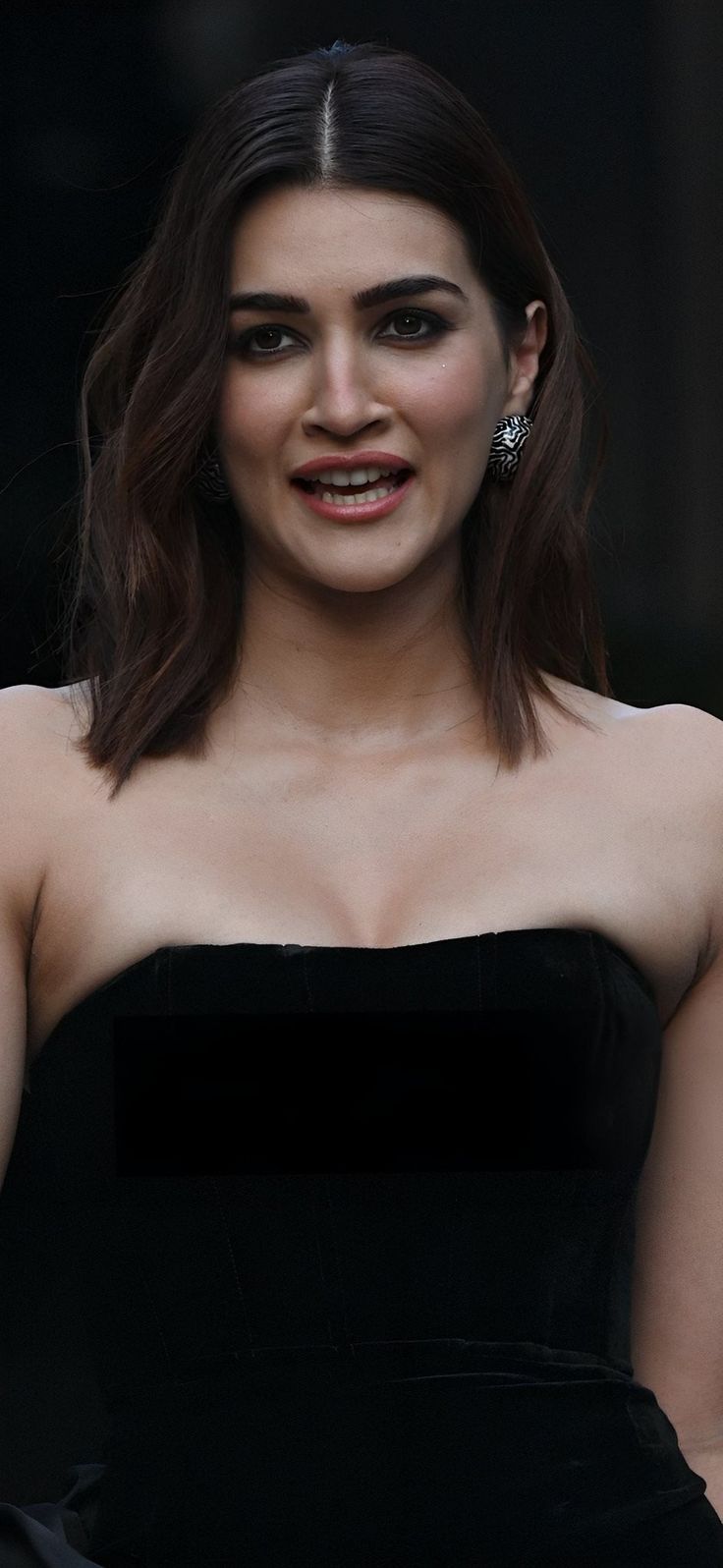 a woman in a black dress is smiling at the camera with her hand on her hip