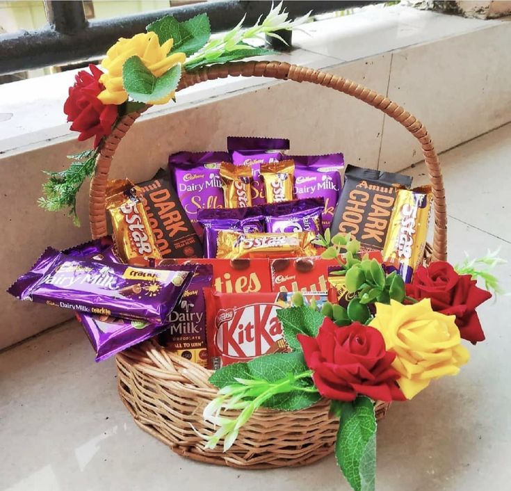 a basket filled with candy and flowers on top of a window sill next to a wall