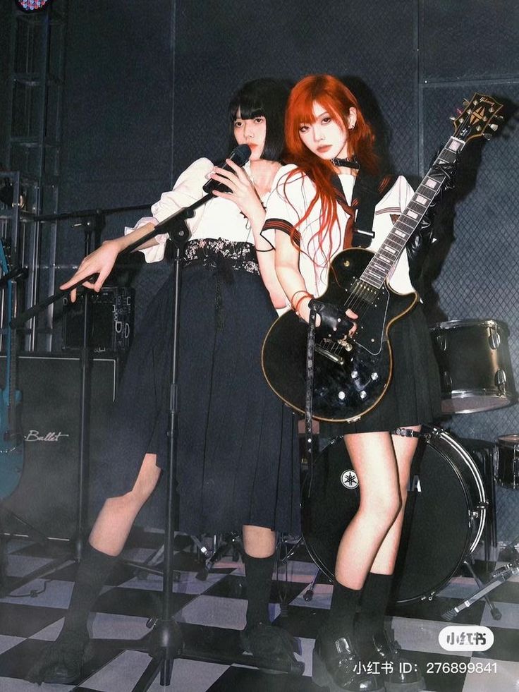 two young women standing next to each other on stage with guitars and microphones in front of them