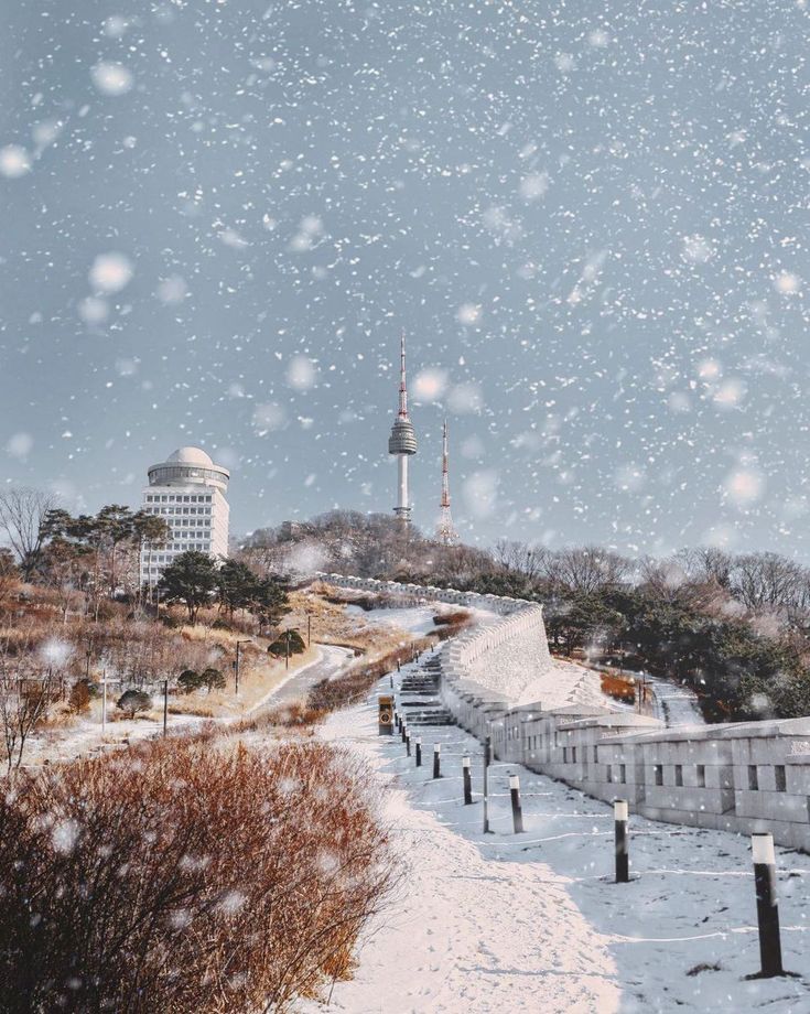 snow falling on the ground and buildings in the background