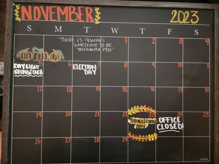 a chalkboard with the calendar for november and december written on it, in front of a wooden shelf