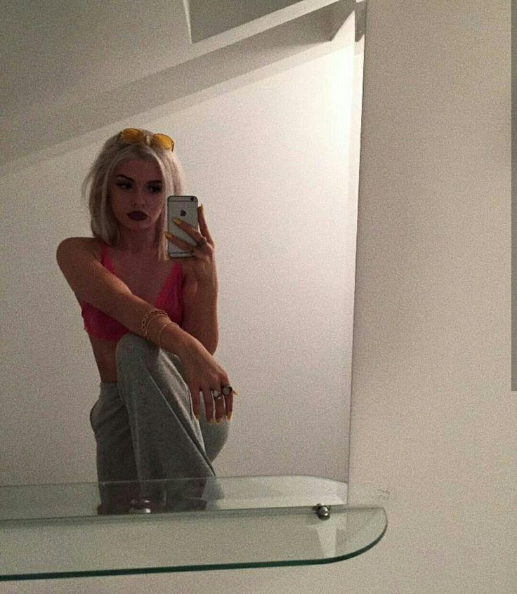 a woman taking a selfie in front of a bathroom mirror with her cell phone